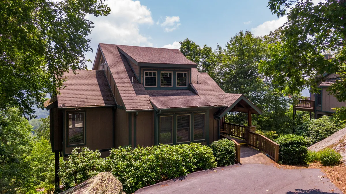 A peaceful exterior shot of the house surrounded by abundant greenery, with a spacious deck area perfect for relaxing or gathering with family and friends. The natural setting stretches out, inviting exploration and connection with the outdoors.