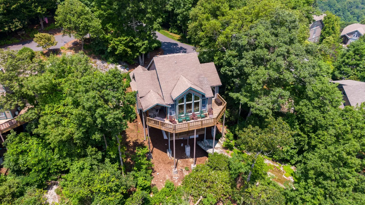 This image captures the exterior of the Echota Ridge Boulders home nestled among trees, with a welcoming balcony that overlooks the lush surroundings. The scene is bathed in soft, natural light, evoking a sense of tranquility and connection to nature.