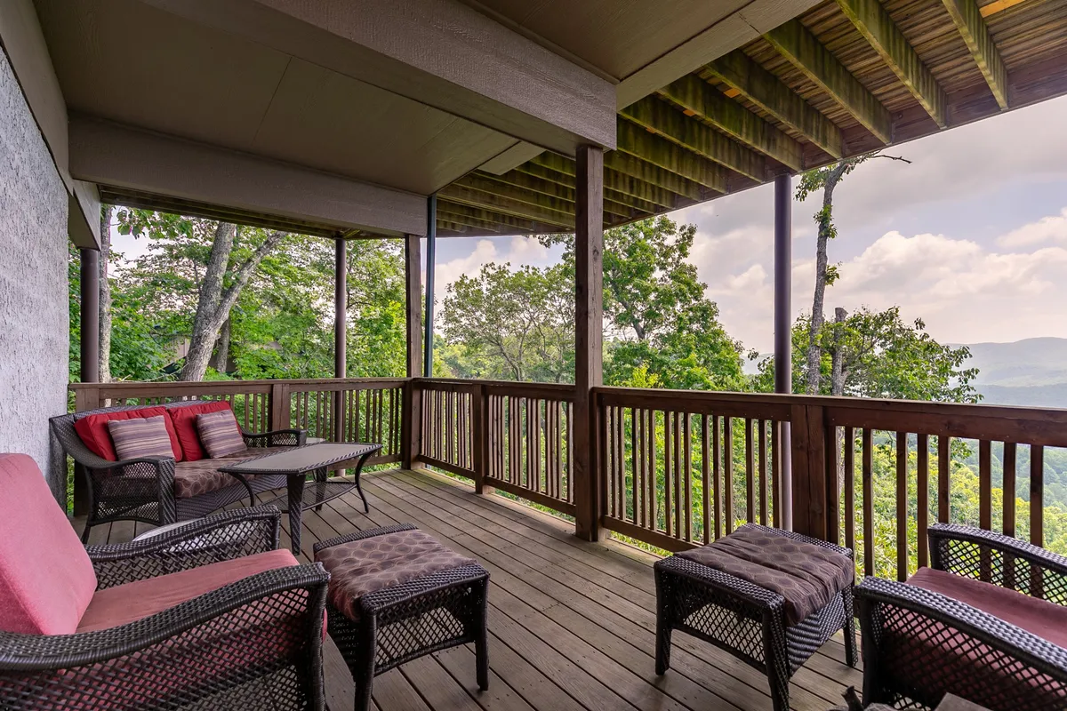 A scenic outdoor seating area framed by a wooden railing with panoramic mountain views in the background. Comfortable chairs invite guests to relax, enjoy morning coffee, or watch the sunrise and sunset amidst the natural beauty of the region.